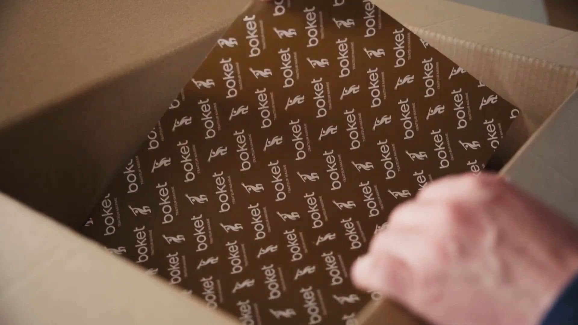 Un carton Boket ouvert sur son papier de soie imprimé, les barquettes à l’intérieur