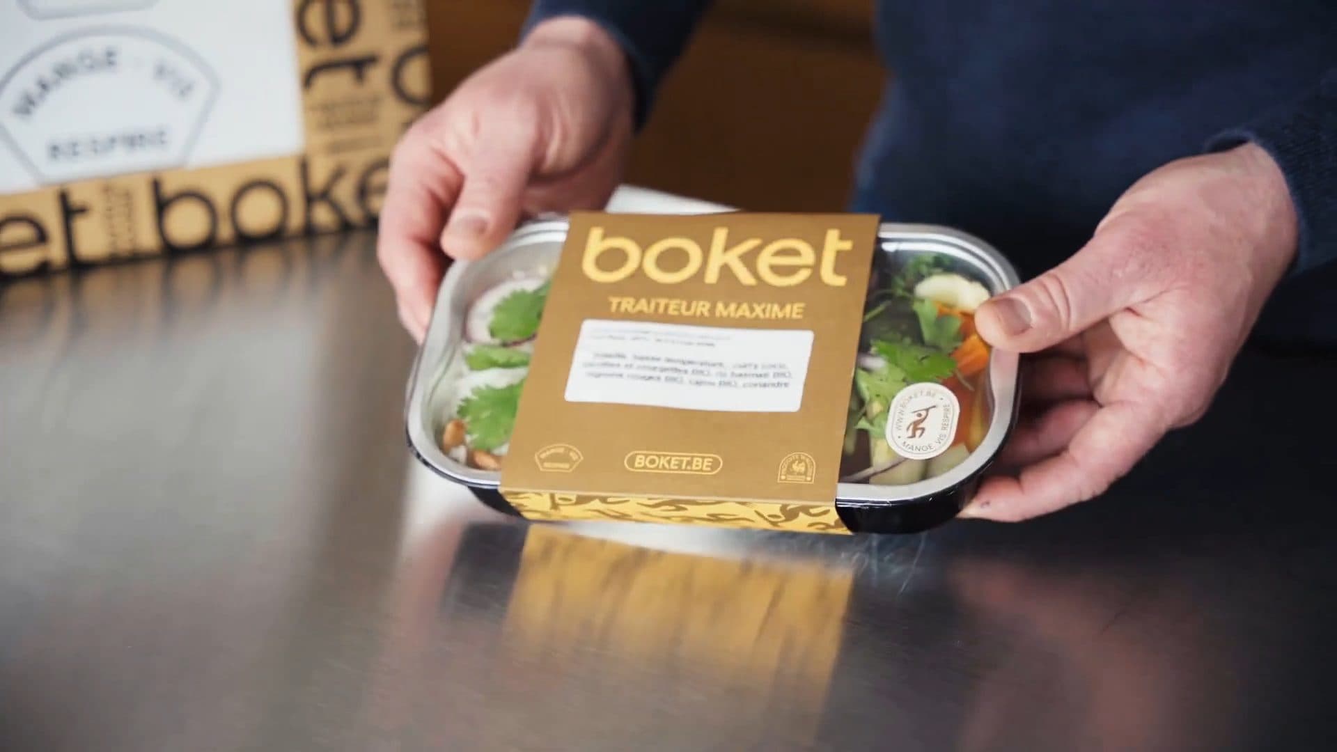 Une barquette Boket Traiteur Maxime, tenue au-dessus du plan de travail